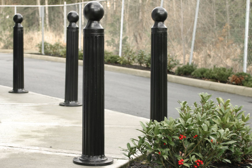 black surface mount bollards line a sidewalk