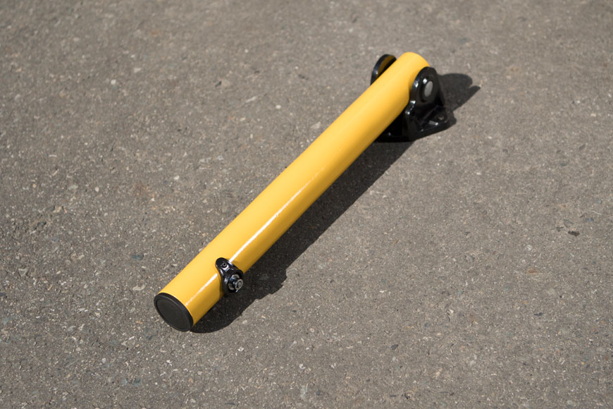 a fold down yellow bollard lies flat against the concrete