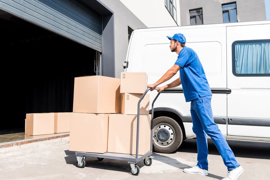 Warehouse worker uses a cart to move heavy boxes