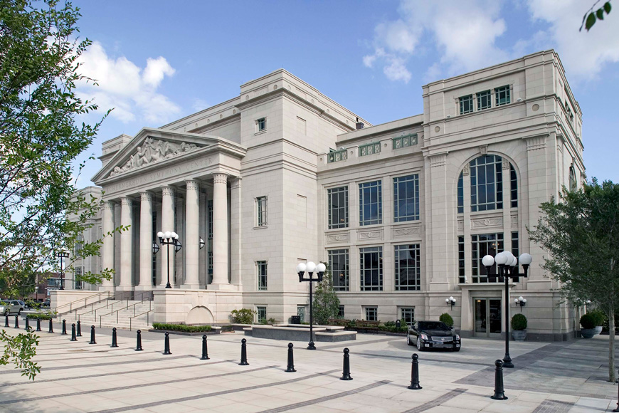 Decorative bollards with ball caps and fluted bodies guard the entrance of a neoclassical building