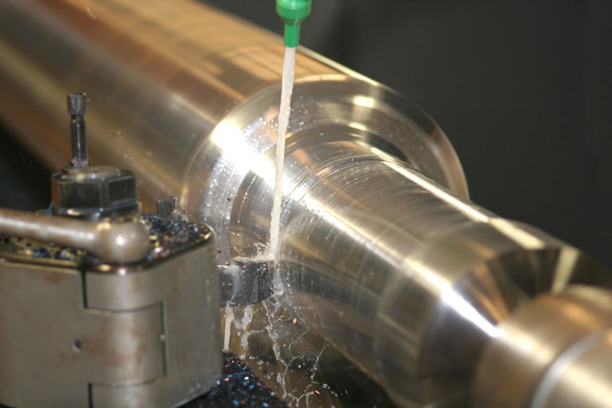 A pickled piece of stainless steel turns on a lathe that carves its diameter