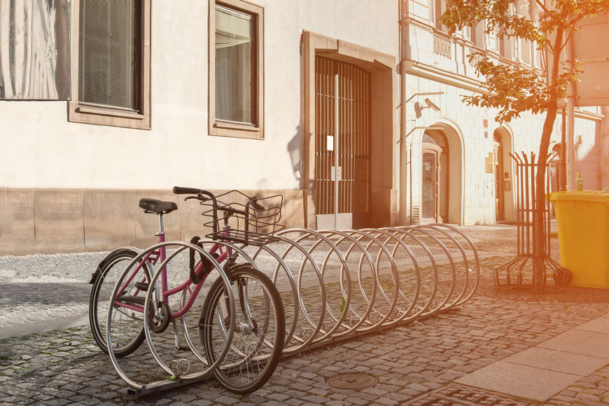 Early morning on European street: a single pink bike is locked to a spiral silver rack.