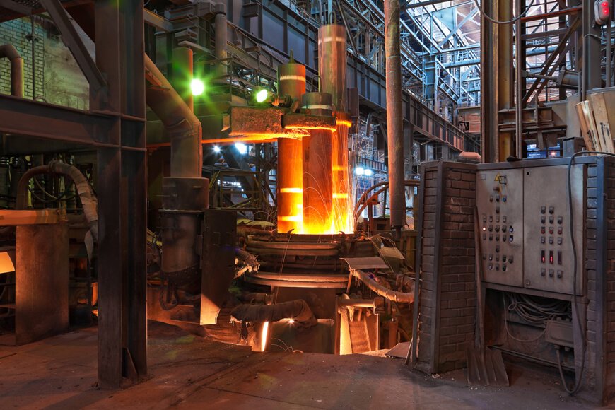 Metal being melted in an electric arc furnace inside a foundry