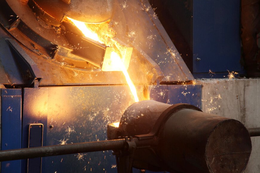 Molten metal being tapped out of an induction furnace into a pouring ladle