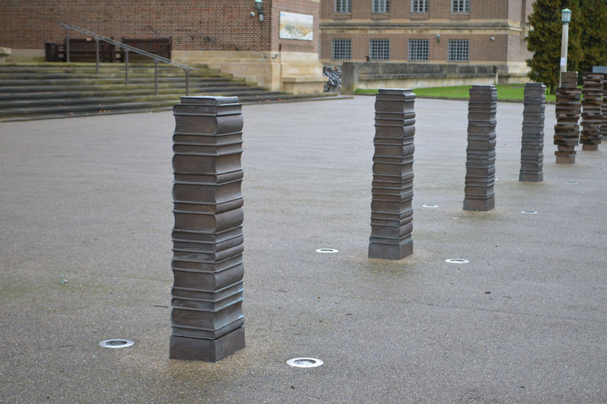 4 bollards looks like neat square stacks of books: three look like stacks where the books are rotated