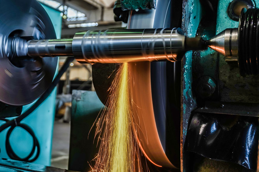 A circular grinder machines a high-precision steel part