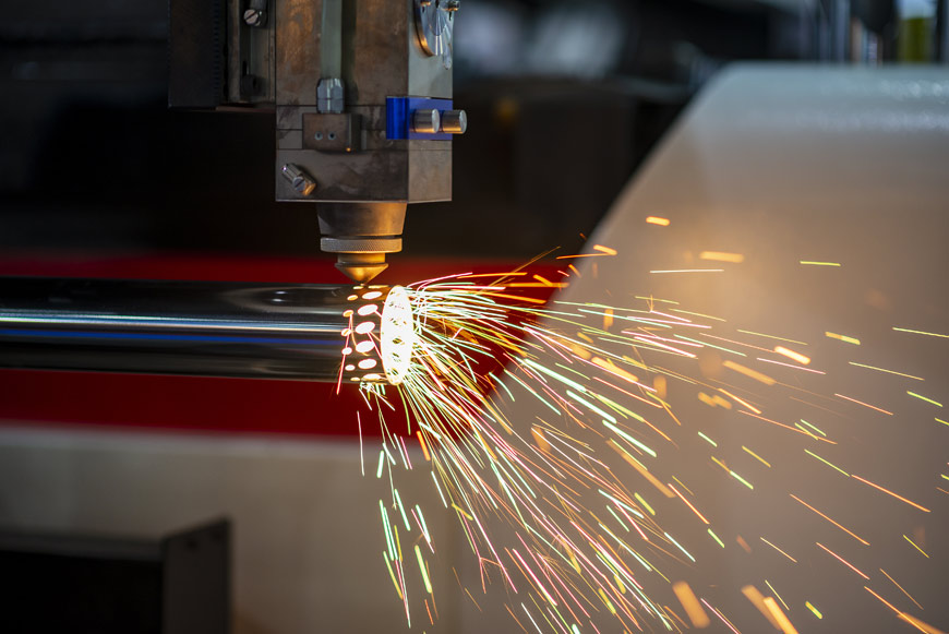 A piece of stainless steel pipe is laser cut using a cnc machine