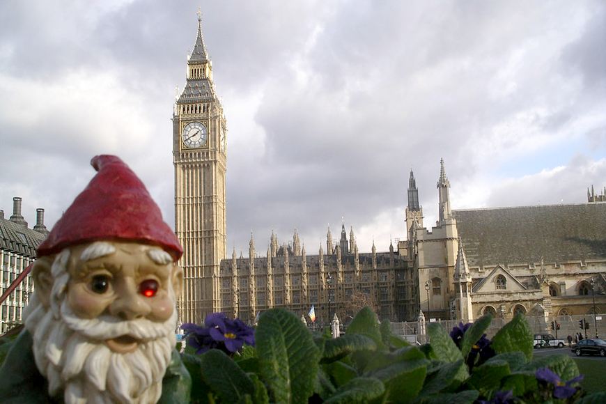 Woody the Travelling Gnome stands in a violet patch with Big Ben in the background