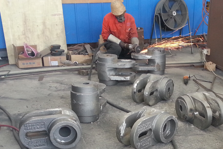 A foundry worker uses an abrasive grinder to remove flashing and other imperfections from a casting