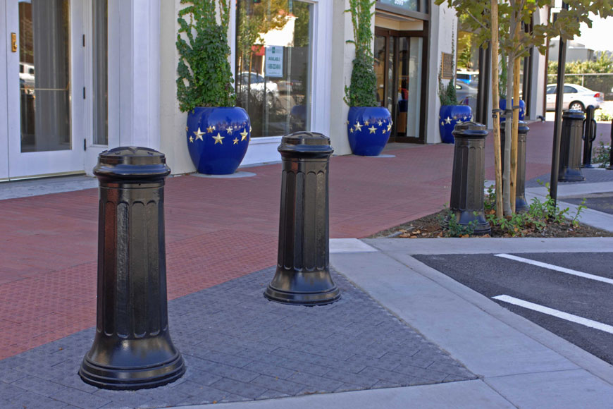 Larger bollards outside a mall are decorated with stars on the cap face